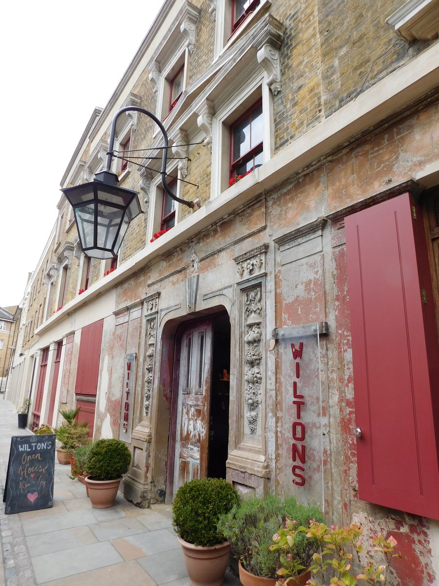 The frontage of Wilton's Music Hall on Graces Alley, showing the entrance door, hanging lamp and red shutters